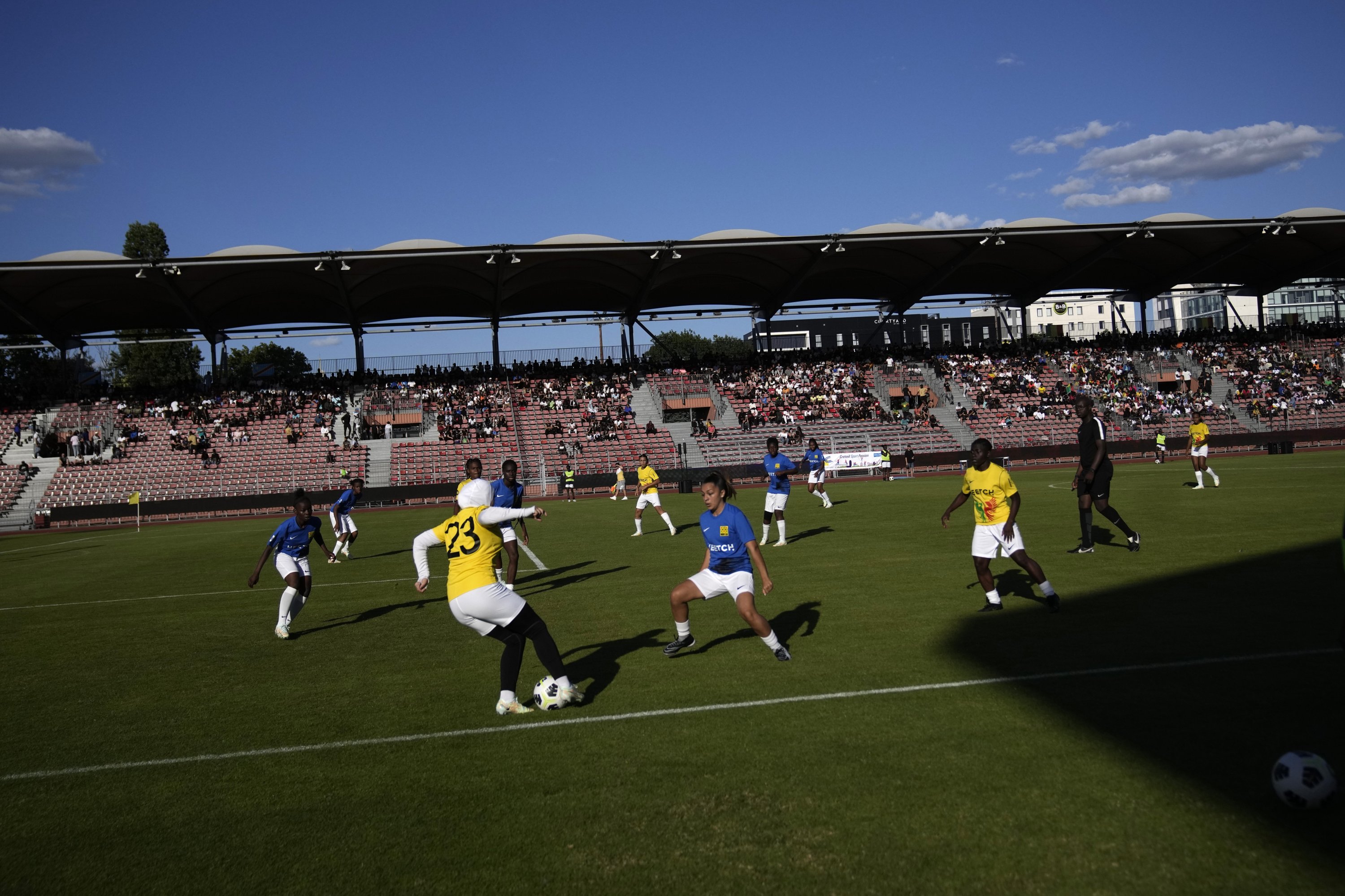 Para pemain menantang selama pertandingan final putri piala nasional lingkungan kelas pekerja antara tim yang mewakili pemain dengan warisan Mali dengan warna kuning melawan satu dengan akar Kongo, Creteil, Prancis, 2 Juli 2022. (AP Photo)