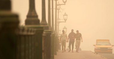 People walk on a bridge during a sandstorm in Baghdad, Iraq, July 3, 2022. (AP Photo)