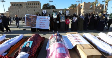 Mourners show portraits near bodies which were exhumed from a mass grave in Tarhuna, before getting reburied in Tripoli, Libya, Jan. 22, 2021. (REUTERS)