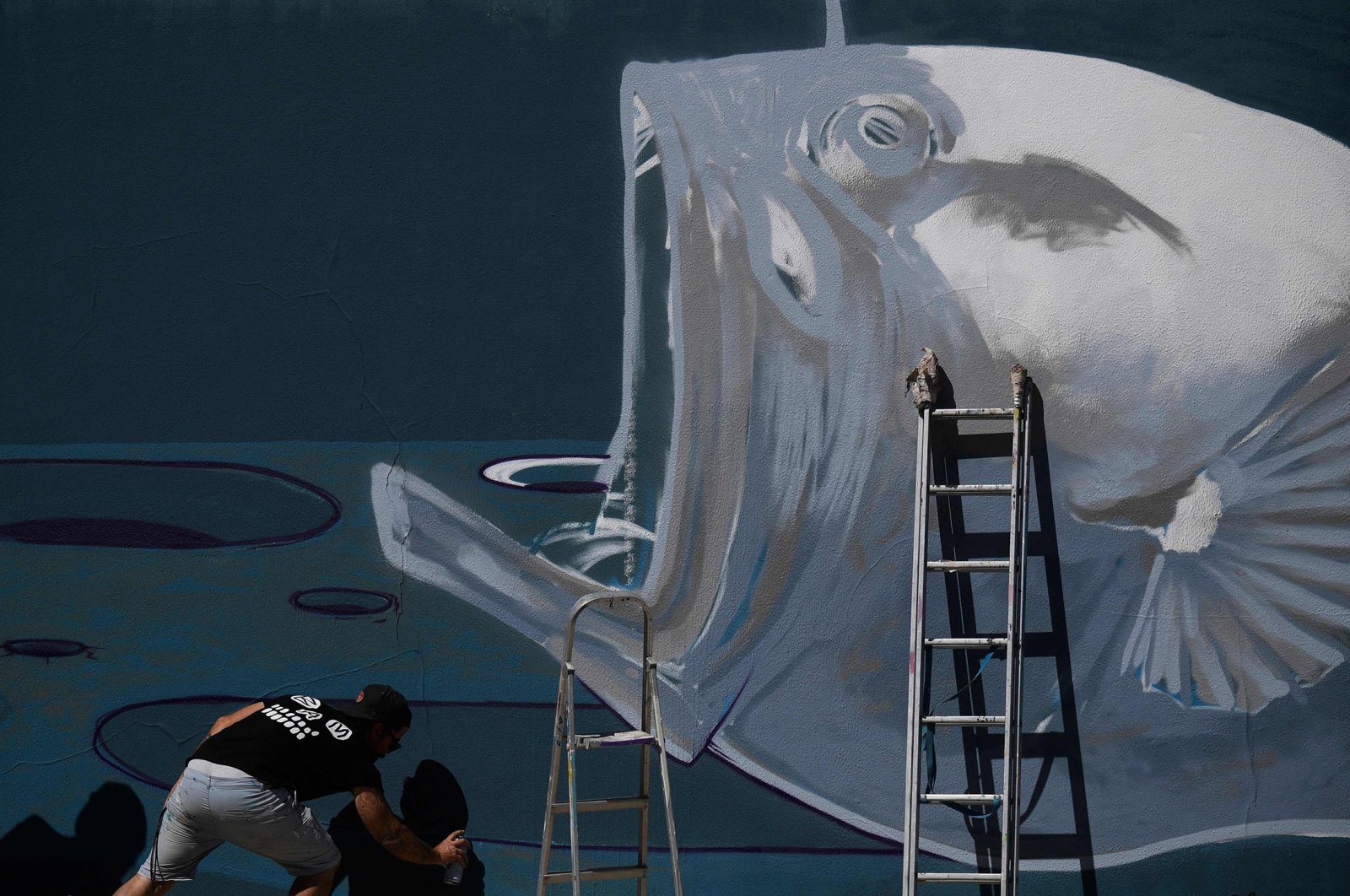 Portuguese graffiti and visual artist Goncalo Mar works on a mural symbolizing the defense of the deep ocean, in Lisbon, Portugal, July 1, 2022. (AFP Photo)