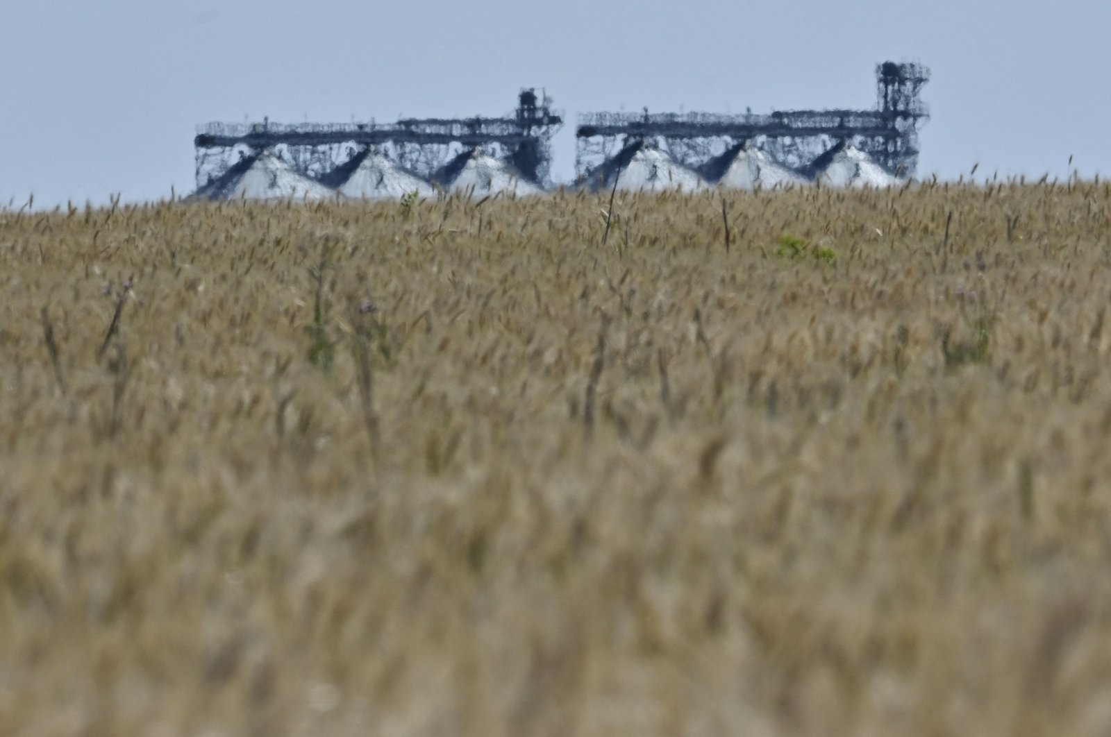 A photograph shows a grain elevator behind a wheat field in Ukraine&#039;s eastern region of Donbas, on July 1, 2022. (AFP Photo)