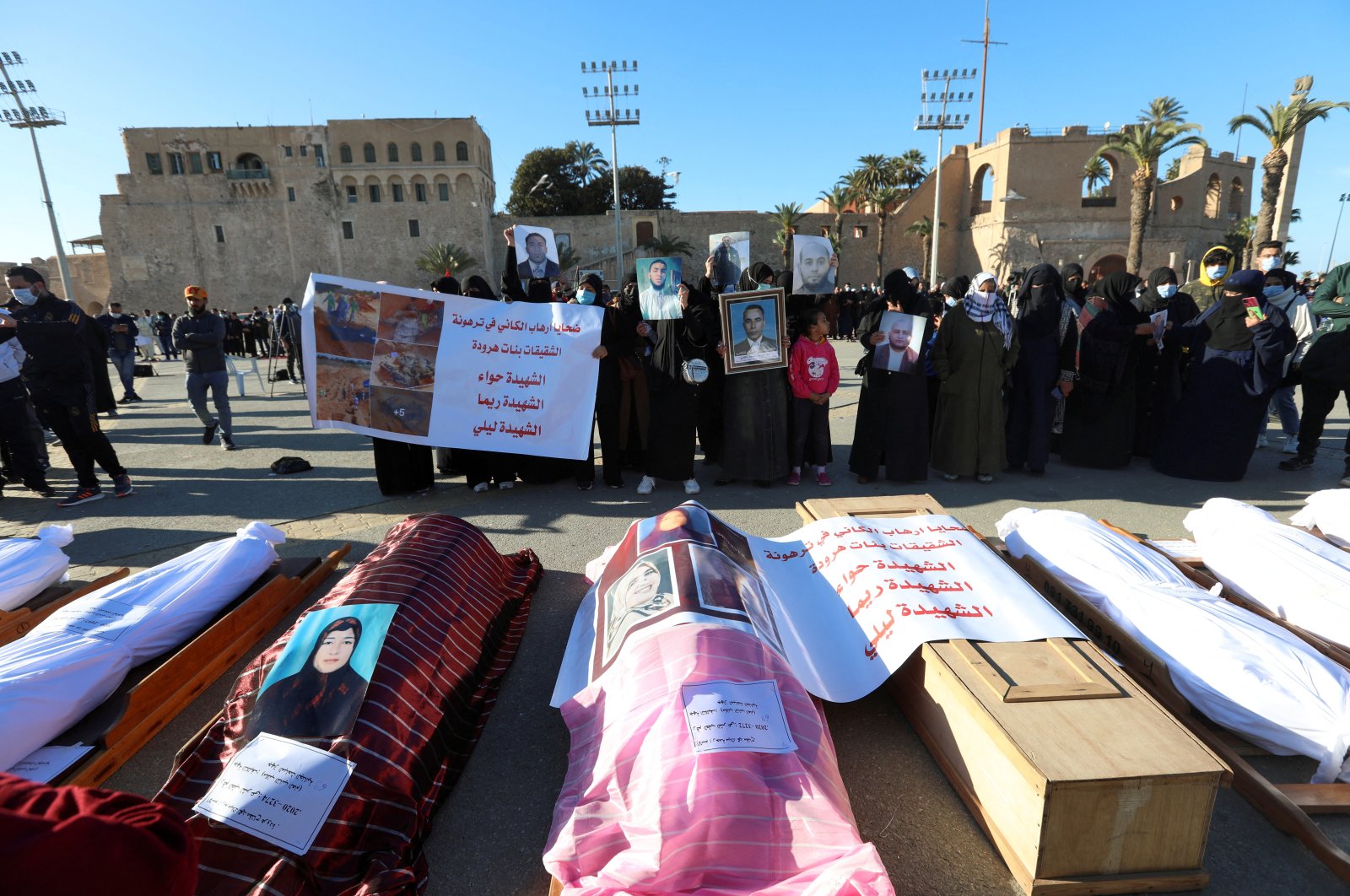 Mourners show portraits near bodies which were exhumed from a mass grave in Tarhuna, before getting reburied in Tripoli, Libya, Jan. 22, 2021. (REUTERS)