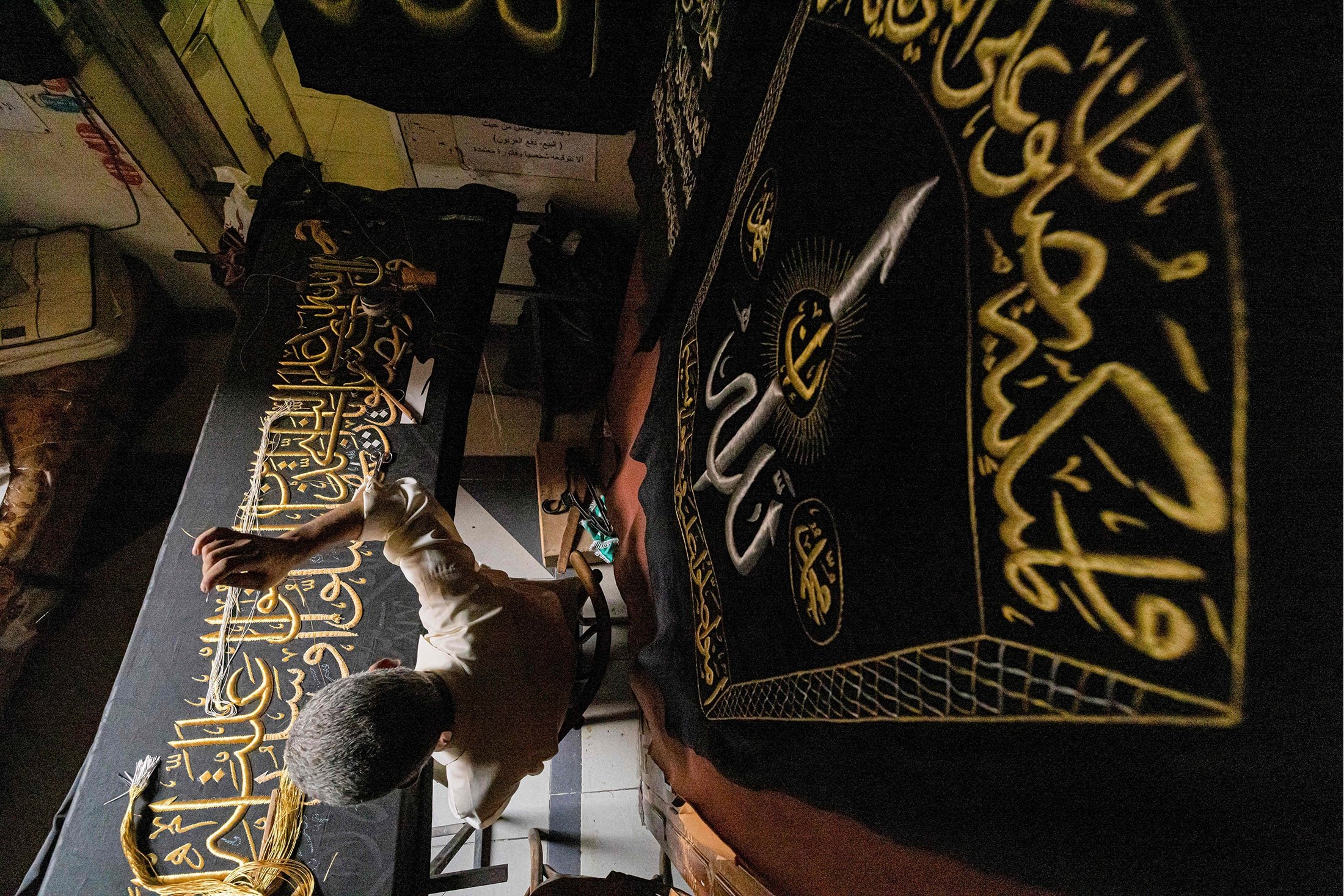 Penyulam Mesir Ahmed Othman el-Kassabgy menjahit dengan benang emas sebuah ayat dari Al-Qur'an ke tirai replika untuk dijual sebagai suvenir bagi wisatawan yang berkunjung ke Kairo, Mesir, 15 Juni 2022. (AFP Photo)