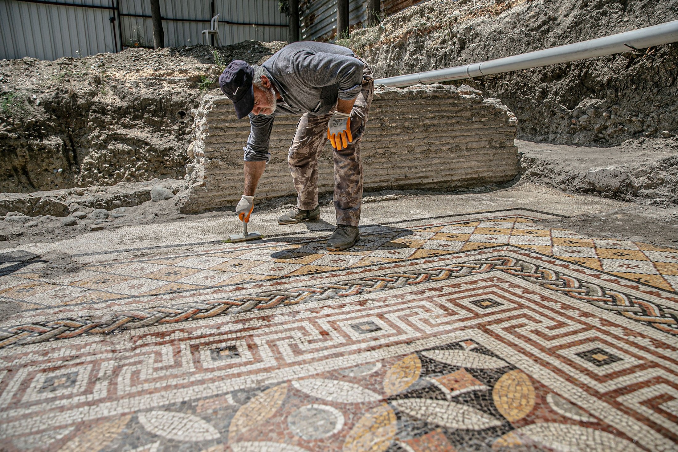 A worker cleans the mosaic on the floor of a recently discovered Roman villa in the Defne district of Hatay, southern Turkey, July 4, 2022. (AA Photo)