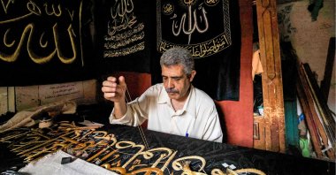 Egyptian embroiderer Ahmed Othman el-Kassabgy sews with gold thread a verse from the Quran onto a replica drape to be sold as a souvenir for tourists visiting Cairo, Egypt, June 15, 2022. (AFP Photo)