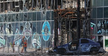 Local residents stand next to a building destroyed during the Ukraine-Russia conflict in the city of Lysychansk in the Luhansk region, Ukraine, July 4, 2022. (Reuters Photo)