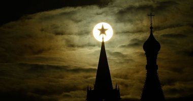 The sun is pictured behind the Kremlin's Spasskaya tower and St. Basil's Cathedral during sunset in downtown Moscow, Russia, April 19, 2022. (AFP Photo)