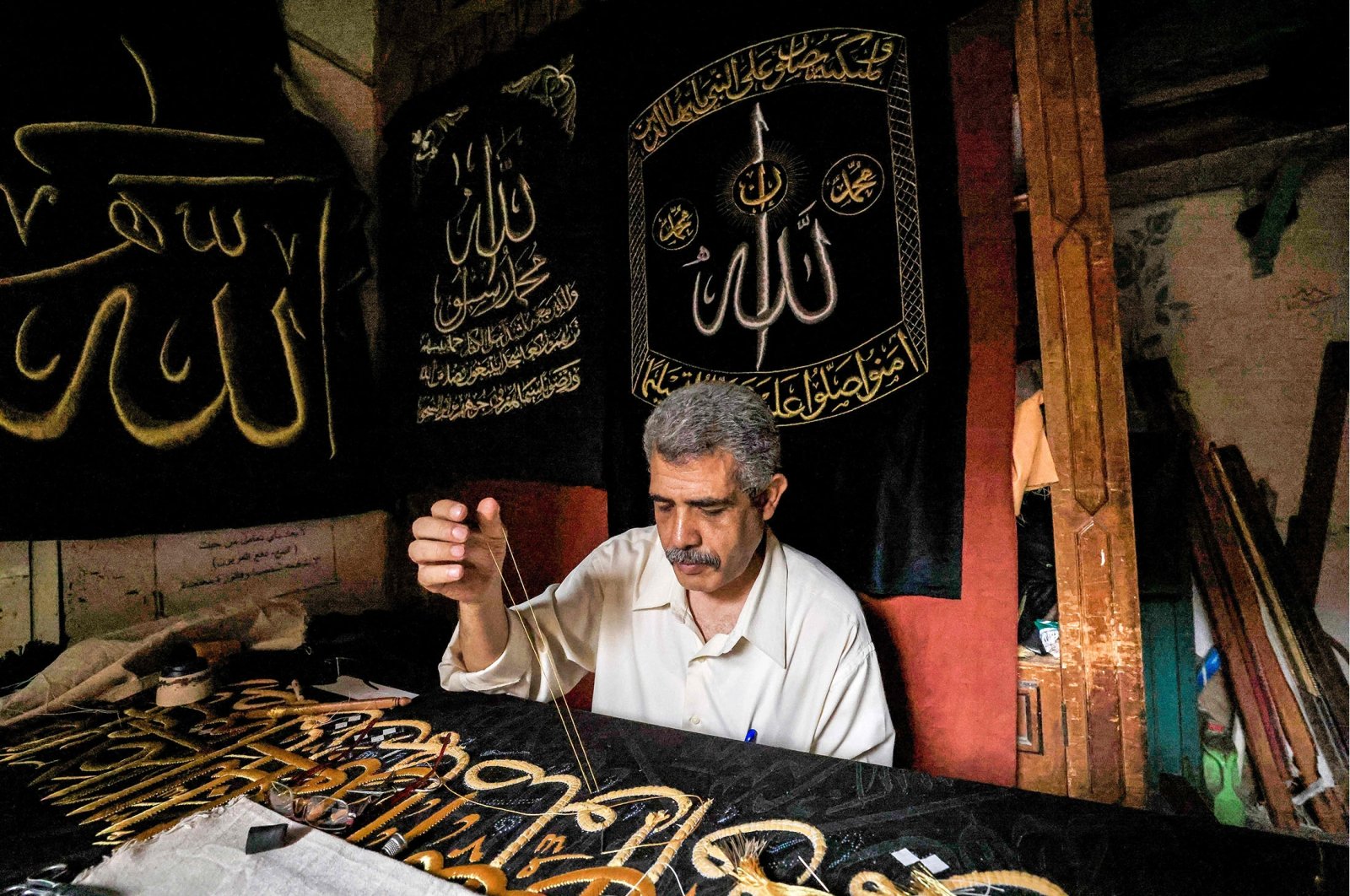 Egyptian embroiderer Ahmed Othman el-Kassabgy sews with gold thread a verse from the Quran onto a replica drape to be sold as a souvenir for tourists visiting Cairo, Egypt, June 15, 2022. (AFP Photo)