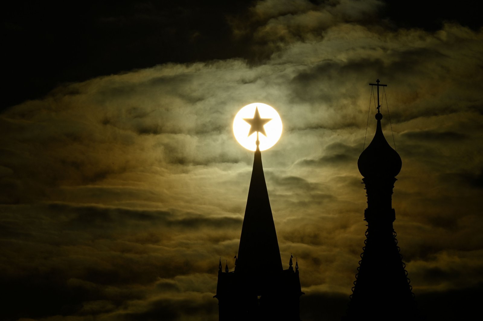 The sun is pictured behind the Kremlin&#039;s Spasskaya tower and St. Basil&#039;s Cathedral during sunset in downtown Moscow, Russia, April 19, 2022. (AFP Photo)