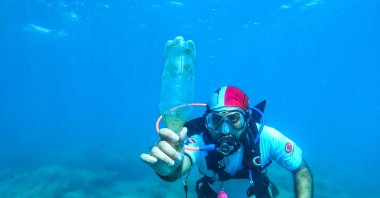 A diver shows the plastic bottle he collected in Mersin, southern Turkey, July 6, 2022. (AA PHOTO)