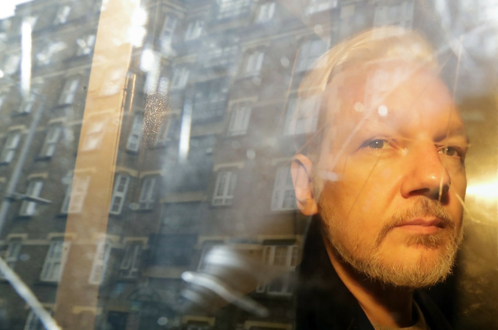 Buildings are reflected in the window as WikiLeaks founder Julian Assange is taken from court, where he appeared on charges of jumping British bail, in London, U.K., May 1, 2019. (AP Photo)