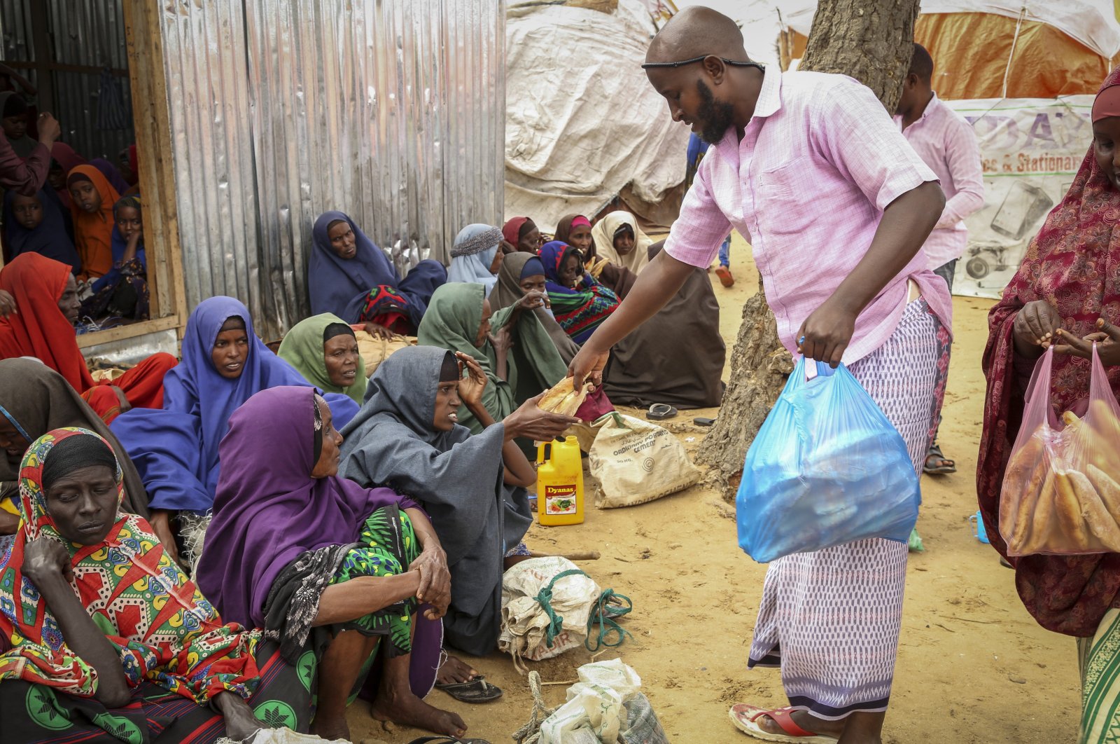 Somalis who fled drought-stricken areas receive charitable food donations from city residents after arriving at a makeshift camp for the displaced on the outskirts of Mogadishu, Somalia, June 30, 2022. (AP Photo)