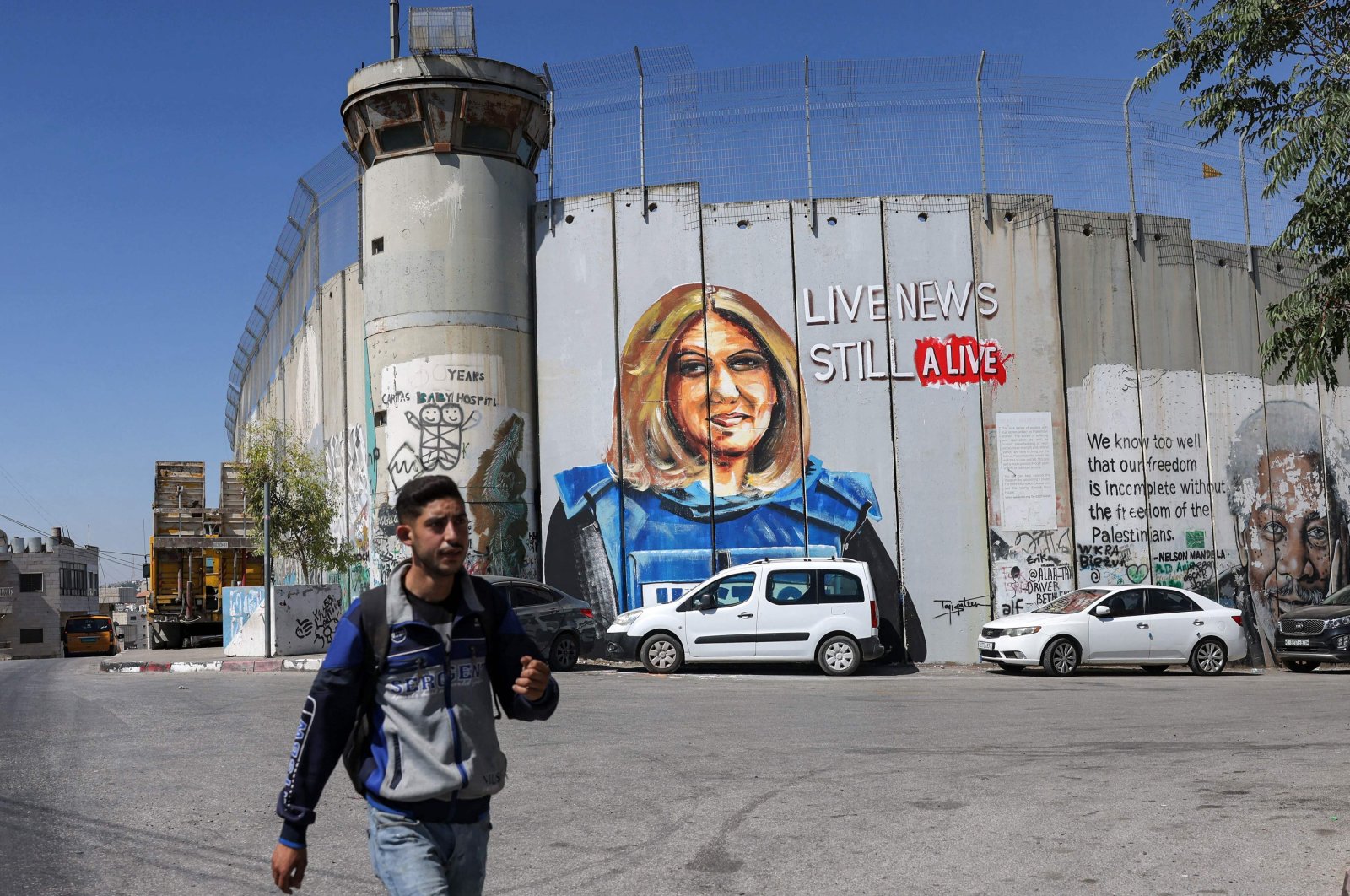 A youth walks past a mural depicting slain Al-Jazeera journalist Shireen Abu Akleh, who was killed while covering an Israeli army raid in Jenin, drawn along Israel&#039;s controversial separation barrier in Bethlehem, West Bank, occupied Palestine, July 6, 2022. (AFP Photo)