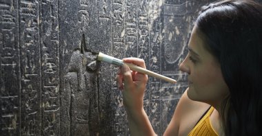 British Museum Senior Conservator Stephanie Vasiliou cleans "The Enchanted Basin", a large black granite sarcophagus covered with hieroglyphs from about 600 B.C., in the Egyptian Sculpture Gallery at the British Museum, London, the U.K. (DPA) 