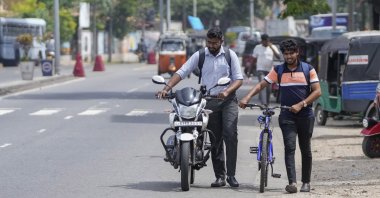 A motorist pushes his motorcycle alongside a cyclist amid fuel shortage in Colombo, Sri Lanka, July 5, 2022. (AP Photo)