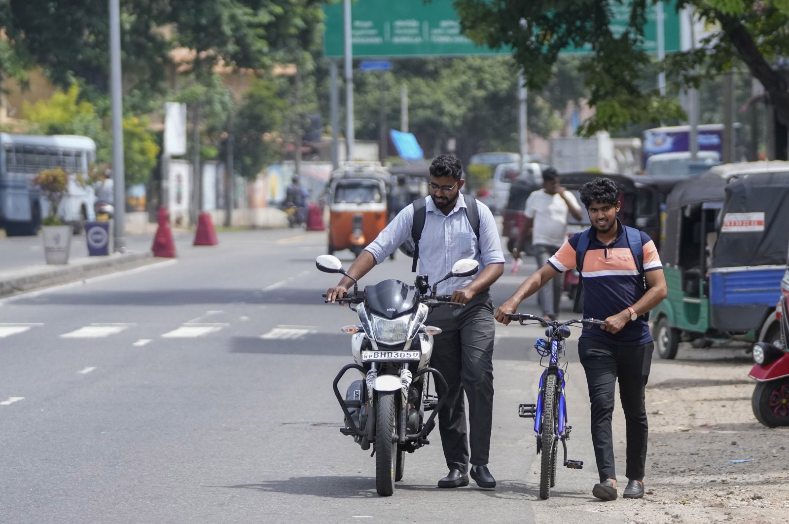A motorist pushes his motorcycle alongside a cyclist amid fuel shortage in Colombo, Sri Lanka, July 5, 2022. (AP Photo)