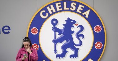 A woman checks her phone outside the Stamford Bridge stadium, London, England, May 7, 2022. (AP Photo)