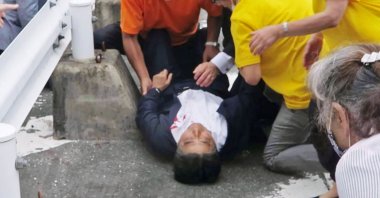 Japan’s former Prime Minister Shinzo Abe (C) is attended on the ground in Nara, western Japan, July 8, 2022. (Kyodo News via AP)