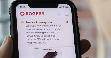 A person looks at their cell phone displaying a Rogers service interruption alert, Montreal, Canada, July 8, 2022. (Graham Hughes/The Canadian Press via AP)
