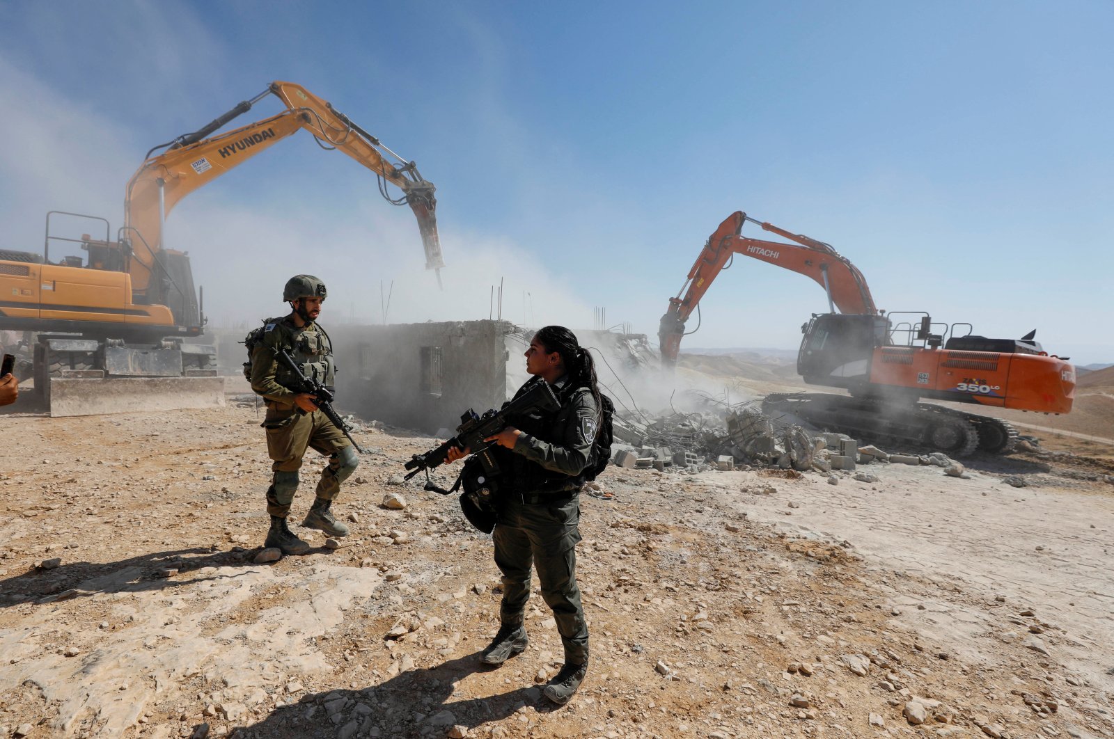 Members of Israeli forces stand guard as Israeli machineries demolish a Palestinian house in Masafer Yatta, in the Israeli-occupied West Bank, Palestine, July 4, 2022. (Reuters Photo)