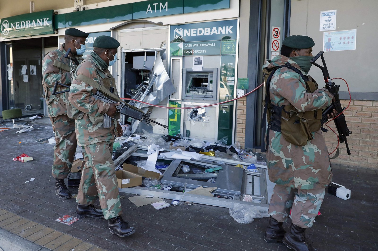 Members of the South African Defence Force walk past an automated teller machine as they patrol the looted Diepkloof Square area in Soweto, Johannesburg, South Africa, July 13, 2021. (AFP File Photo)