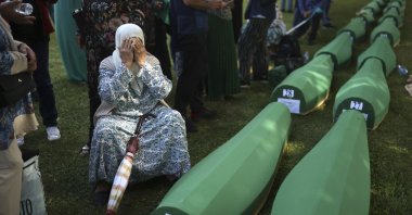 A Bosnian Muslim woman mourns next to the coffin containing remains of her husband who is among 50 newly identified victims of Srebrenica Genocide in Potocari, Bosnia-Herzegovina, July 11, 2022. (AP Photo)
