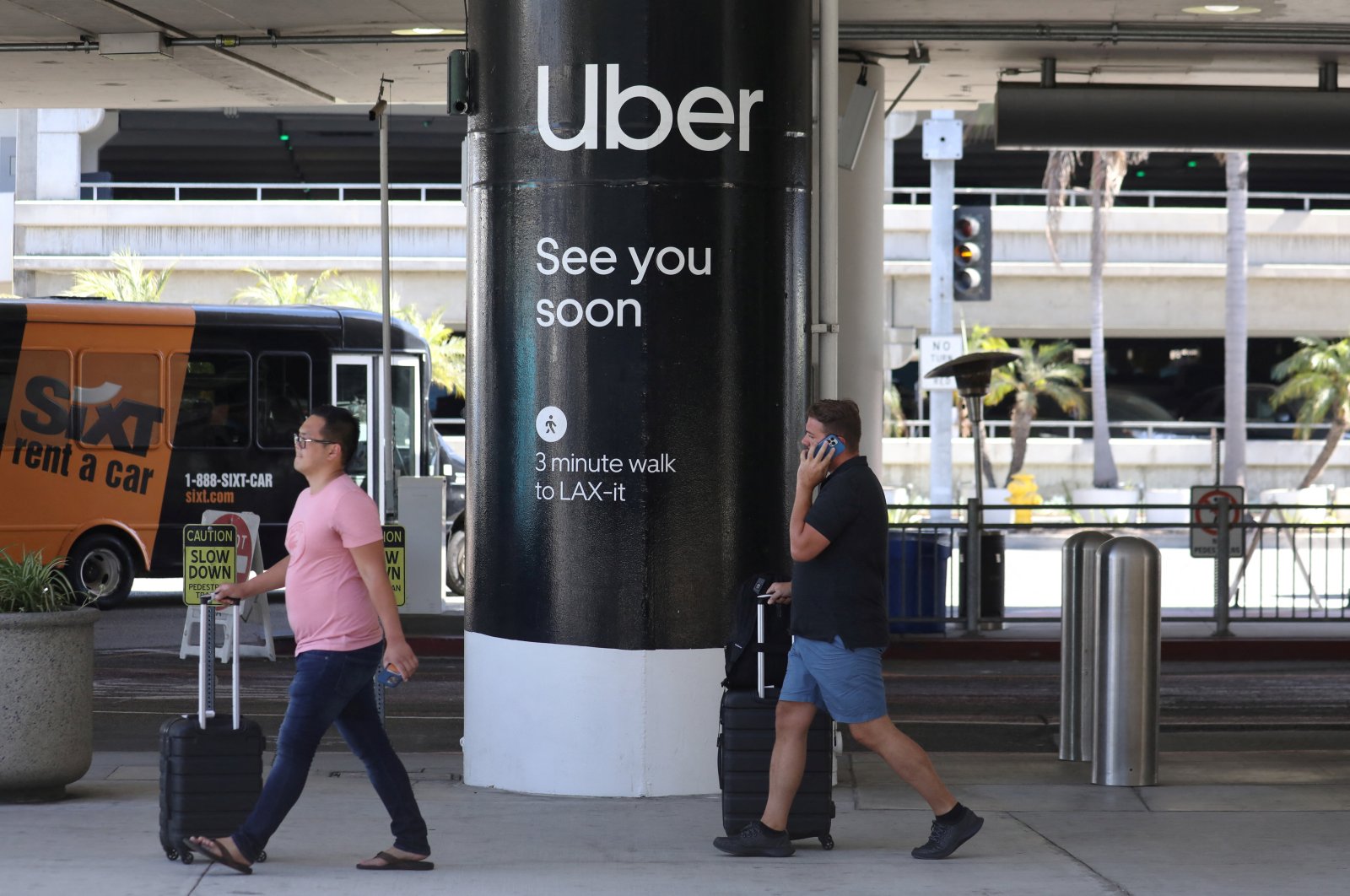 Passengers walk near Uber ride-share signage after arriving at Los Angeles International Airport (LAX) in Los Angeles, California, U.S., July 10, 2022. (Reuters Photo)