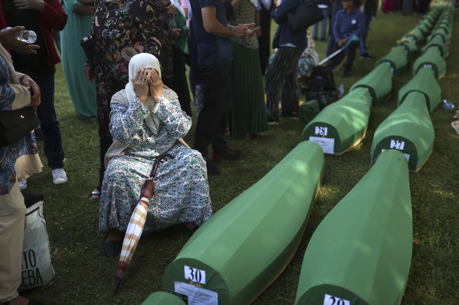 A Bosnian Muslim woman mourns next to the coffin containing remains of her husband who is among 50 newly identified victims of Srebrenica Genocide in Potocari, Bosnia-Herzegovina, July 11, 2022. (AP Photo)