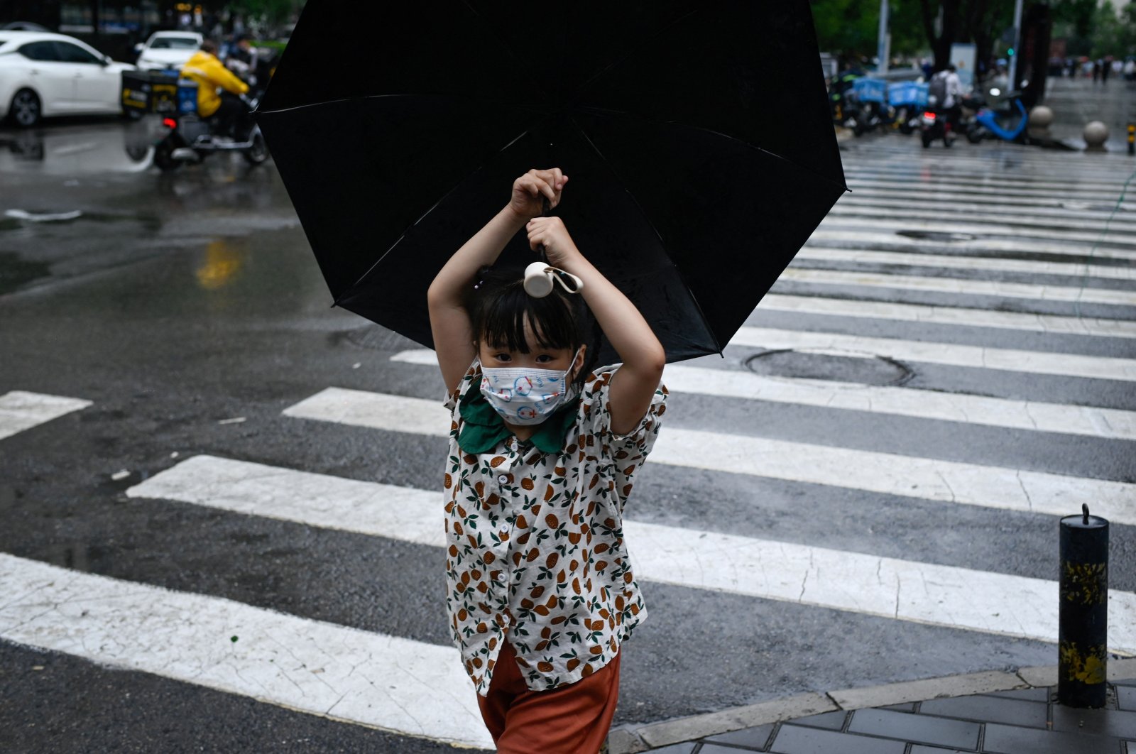 A child holding an umbrella crosses a street in Beijing, China, July 12, 2022. (AFP Photo)
