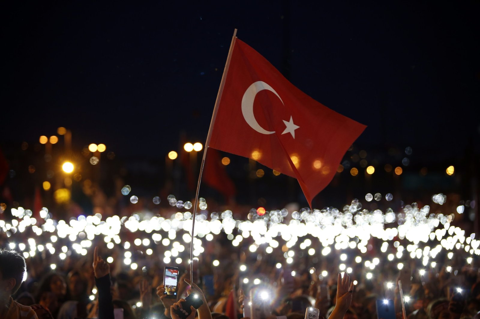 Ihmiset käyttävät matkapuhelimiaan taskulamppuina osallistuessaan 15. heinäkuuta epäonnistuneen vallankaappausyrityksen toisen vuosipäivän muistotapahtumaan Istanbulissa, Turkissa, 15. heinäkuuta 2018. (AP-kuva)