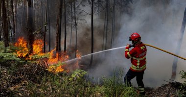 A firefighter uses a hose during firefighting operations at Espite in Ourem, Portugal, July 13, 2022. (AFP Photo)