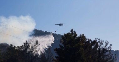 A helicopter drops water to extinguish a wildfire in Datça, Turkey July 14, 2022. (Reuters Photo)