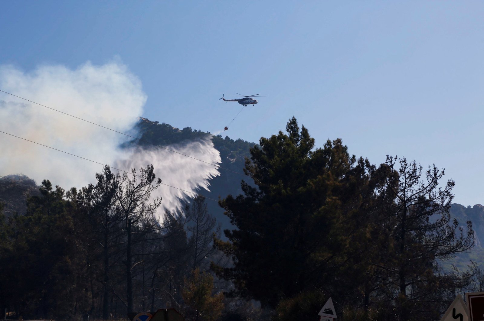 A helicopter drops water to extinguish a wildfire in Datça, Turkey July 14, 2022. (Reuters Photo)