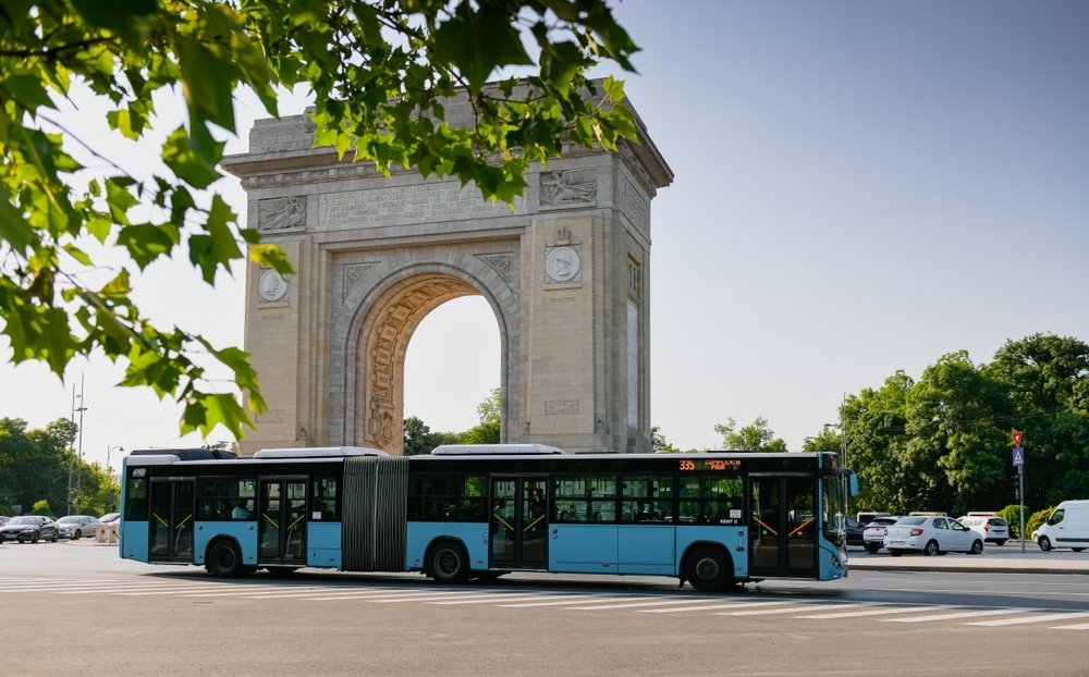 An Otokar bus of the Bucharest STB (Transportation Society) drives in traffic in the north of the city next to the Arch of Triumph, Romania, 2022. (Shutterstock Photo)