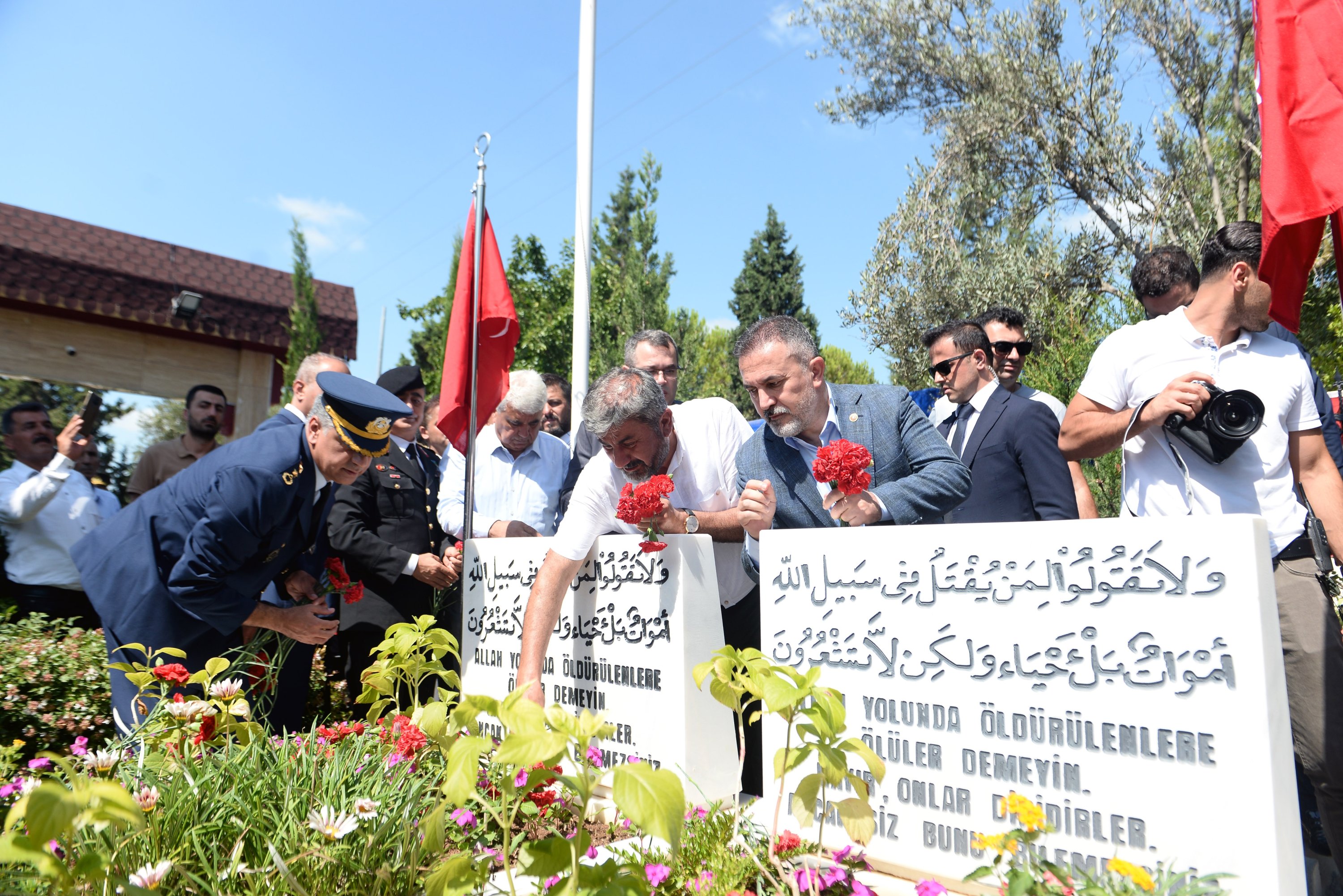 Hacı Ali Oruç (2nd L) leaves flowers on the graves of his two sons killed by putschists, in Adana, southern Turkey, July 15, 2022. (DHA PHOTO)
