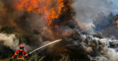 A firefighter fights the flames surrounding Ancede village during a wildfire in the municipality of Baiao, north of Portugal, July 15, 2022. (EPA-EFE Photo)