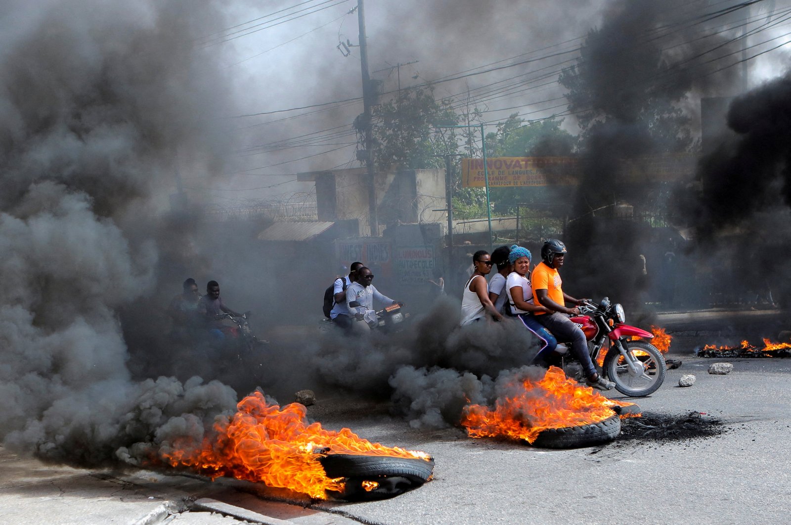 Motorcycle drivers pass through a burning roadblock as anger mounted over fuel shortages that have intensified as a result of gang violence, in Port-au-Prince, Haiti, July 13, 2022. (Reuters File Photo)