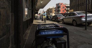A street hawker walks past a generator being used by an internet cafe in Johannesburg, South Africa, Sept. 8, 2017. (AFP Photo) 