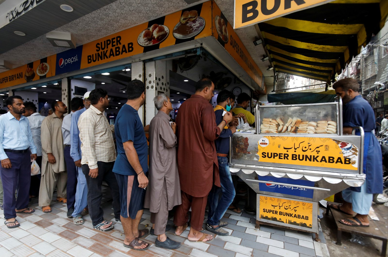 People wait for their turn to buy low-priced bun-kabab from a shop in Karachi, Pakistan, June 10, 2022. (Reuters Photo)