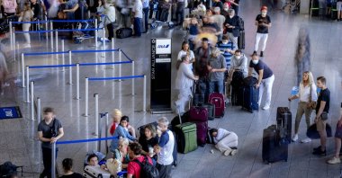 A woman rests in a queue at a check-in terminal at the international airport in Frankfurt, Germany, July 2, 2022. (AP Photo)