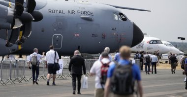 Visitors walk past planes at the Farnborough International Airshow in Farnborough, England, July 18, 2022. (AP Photo)