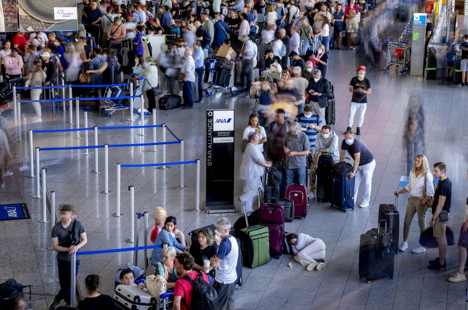 A woman rests in a queue at a check-in terminal at the international airport in Frankfurt, Germany, July 2, 2022. (AP Photo)