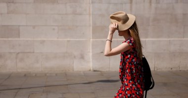 A woman uses a hat to shield her face from the sun in Trafalgar Square during the hot weather in London, Britain, July 18, 2022. (Reuters Photo)