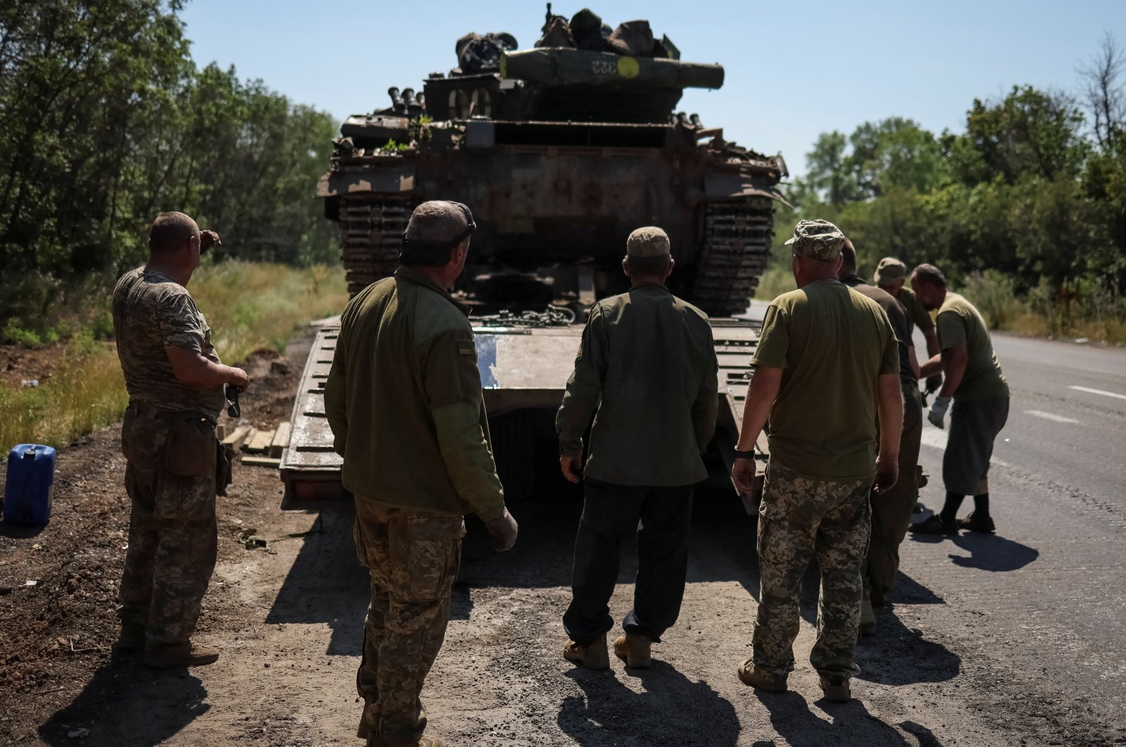 Ukrainian servicemen stand near a military truck with a tank on the road not far from front line, the Donbass region, Ukraine, July 17, 2022. (Reuters Photo)