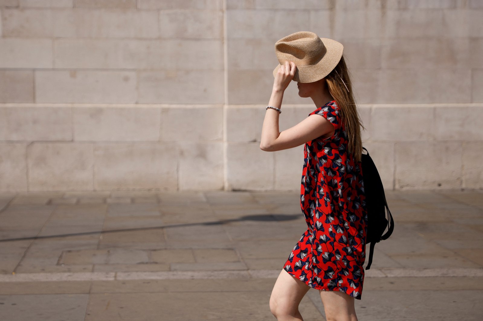 A woman uses a hat to shield her face from the sun in Trafalgar Square during the hot weather in London, Britain, July 18, 2022. (Reuters Photo)