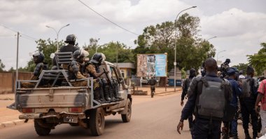 Security forces drive a vehicle near a crowd gathering awaiting the return of Blaise Compaore, former president of Burkina Faso, in front of Ouagadougou airport on July 7, 2022, eight years after he was forced into exile in Ivory Coast in 2014. (AFP Photo)