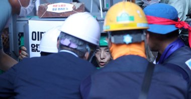 South Korea's Employment and Labor Minister Lee Jung-sik talks with Yoo Choi-ahn, vice chief of the subcontractor union, stuck inside a steel cage-like structure after welding himself to the floor of the occupied oil tanker during a strike at Daewoo Shipbuilding &amp; Marine Engineering in Geoje, South Korea, July 19, 2022. (Yonhap via Reuters )