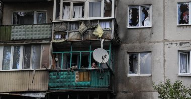 A local resident looks out through a broken window in her flat in a residential building damaged by a Russian military strike in Kramatorsk, Donetsk region, Ukraine, July 19, 2022. (Reuters Photo)