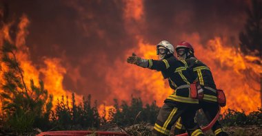 This photo provided by the fire brigade of the Gironde region (SDIS 33) shows firefighters unrolling a fire hose at a forest fire at La Test-de-Buch, southwestern France, July 18, 2022. France scrambled to coordinate more water-bombing planes and hundreds more firefighters to combat spreading wildfires that were being fed Monday by hot swirling winds from a searing heat wave broiling much of Europe. (SDIS 33 via AP)