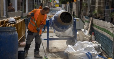 A construction worker cleans the pavement while rehabilitating a street in Barcelona, Spain, Wednesday, July 20, 2022. (AP Photo)